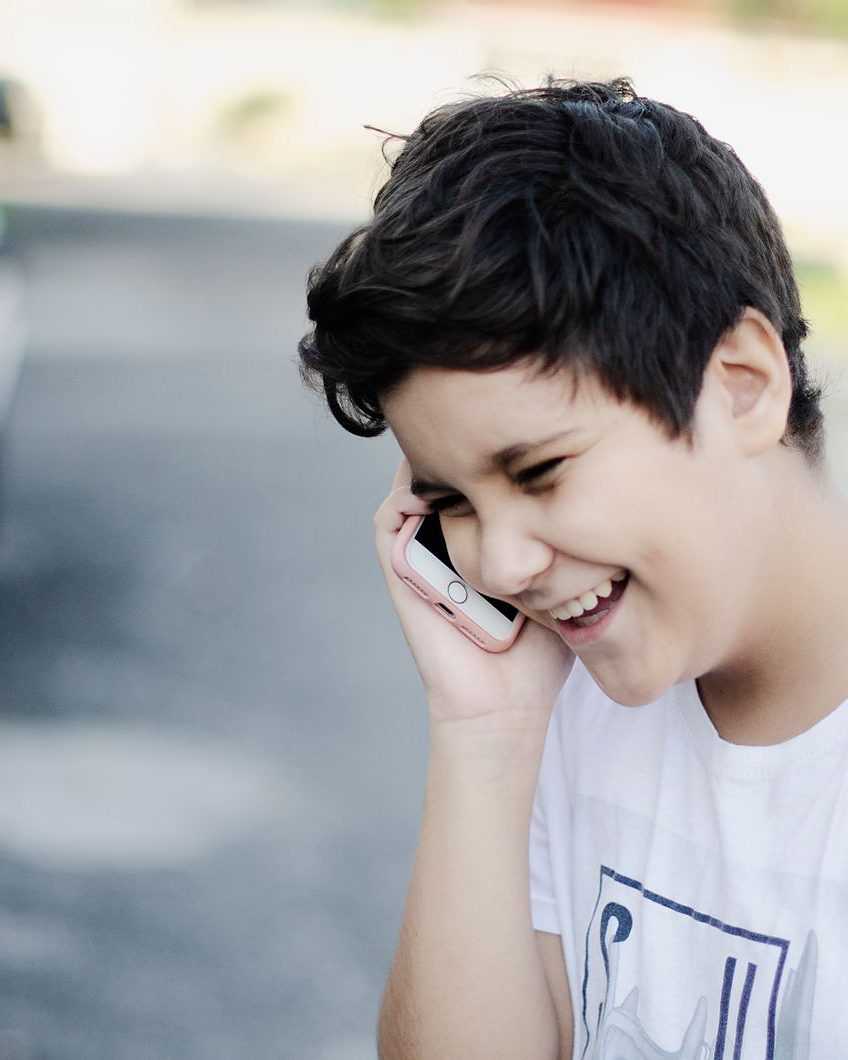 Un bambino che tiene il telefono premuto contro l&rsquo;orecchio e ascolta