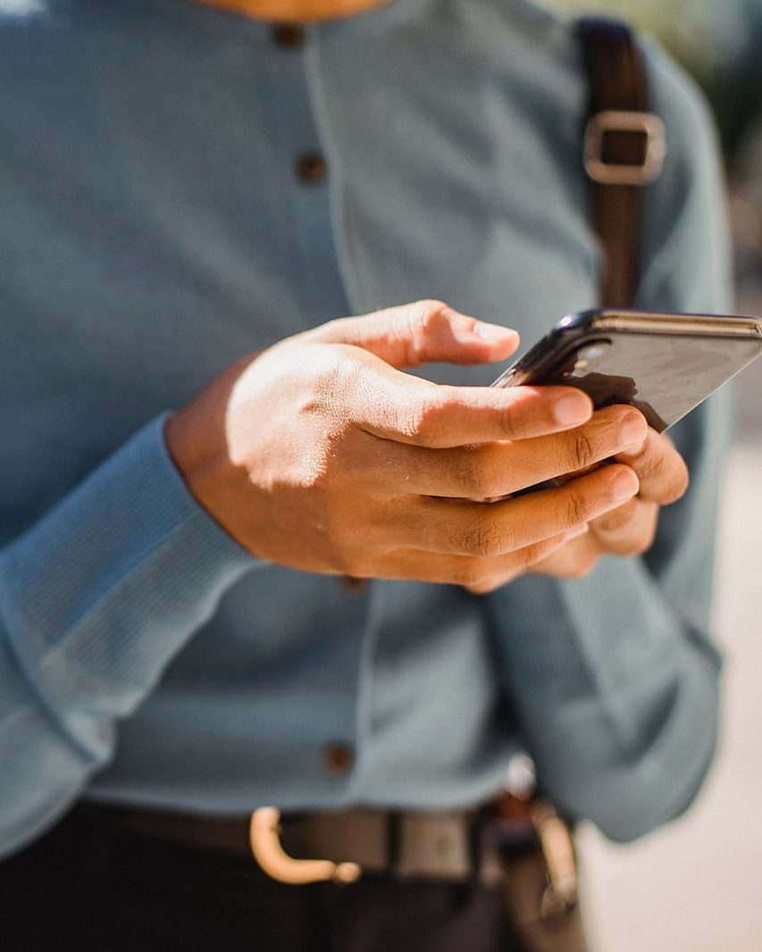 Un uomo che tiene lo smartphone con due mani, il pollice sopra lo schermo